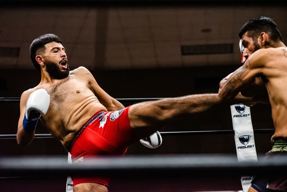 Fighter in red shorts landing a body kick