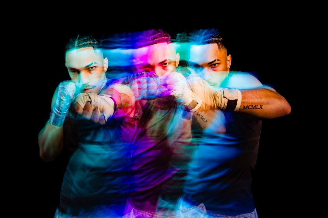 Multi-exposure portrait of a boxer throwing a punch in streaks of neon colour