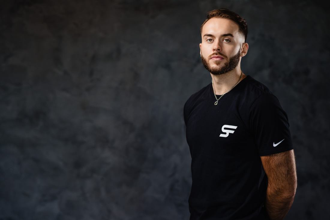 Studio portrait of a bearded athlete in a black T-shirt against a dark painted backdrop