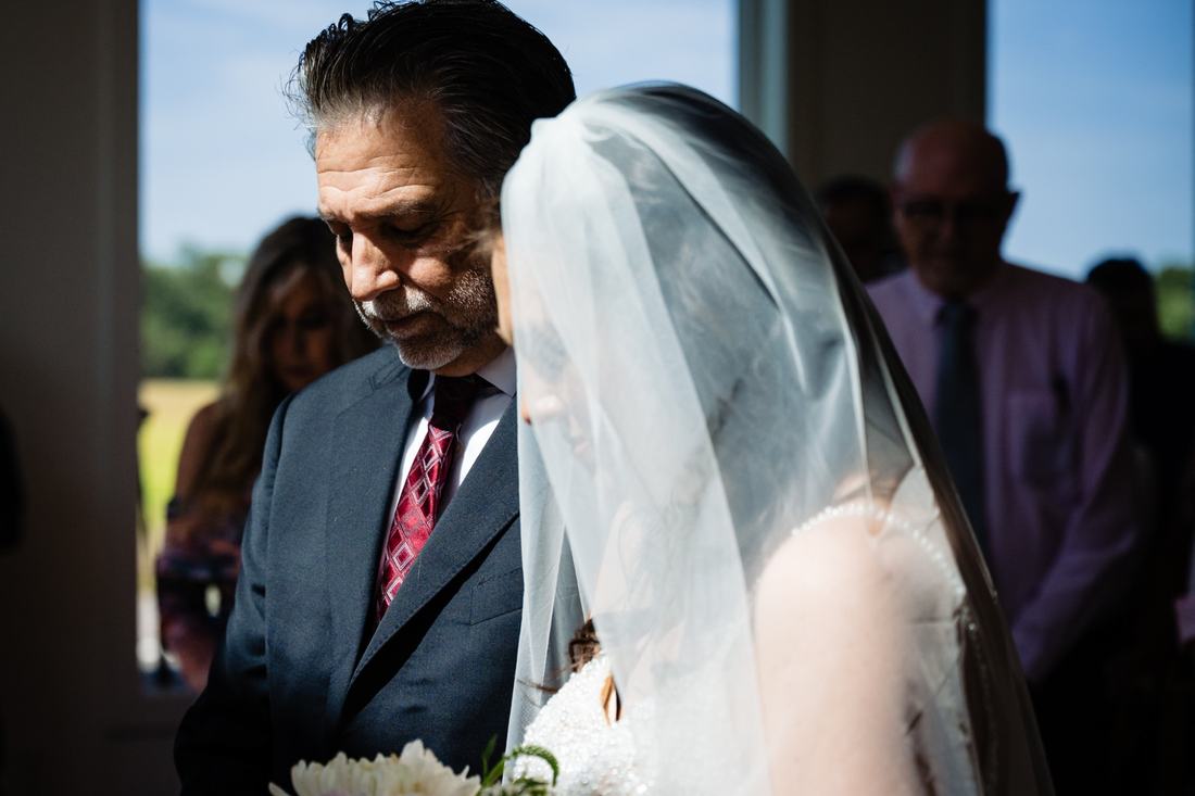Father of the bride bowing his head beside his veiled daughter before the ceremony